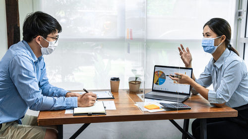 Business people wearing mask having discussion in office