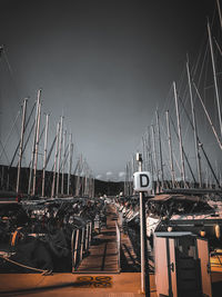 Sailboats moored at harbor against sky