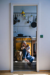 Woman sitting on floor in kitchen at home