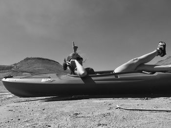 Side view of woman lying on beach against sky