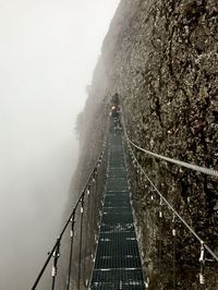 Snow covered footbridge against sky during foggy weather