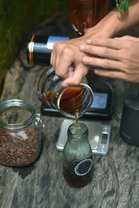 Midsection of man pouring coffee in jar on table