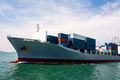 Wide angle in front container ship and tugboat dragging floating in green sea, business 