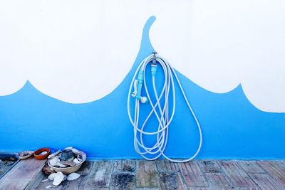 Garden hose wrapped around tap on blue wall in back yard
