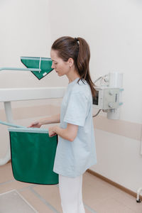 Side view of young woman using digital tablet while standing in hospital