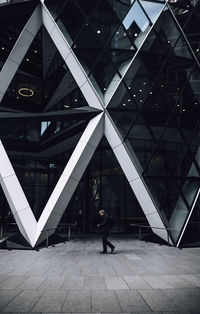 Full length of man standing at illuminated modern building