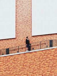 Low angle view of man standing on steps against brick wall