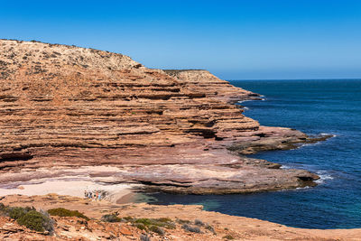 Rock formations on shore against clear sky
