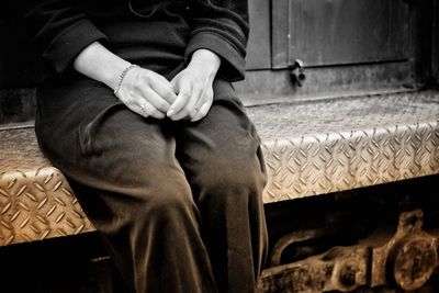 Midsection of woman sitting on sheet metal