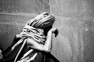 Side view of woman sitting against wall