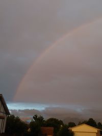 Rainbow over houses against sky