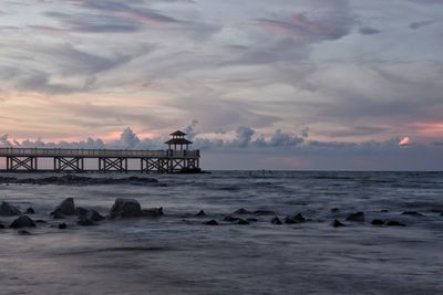 Pier over sea against sky during sunset