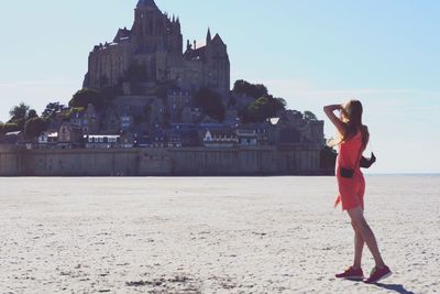 Full length of woman standing on beach against sky