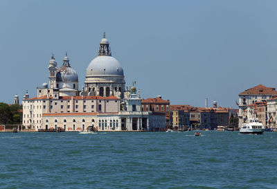 View of buildings by canal against clear sky