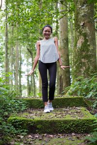 Young woman with umbrella walking in forest