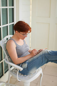 Young woman using phone while sitting on chair