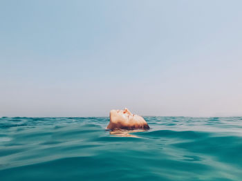 Person swimming in sea against clear sky