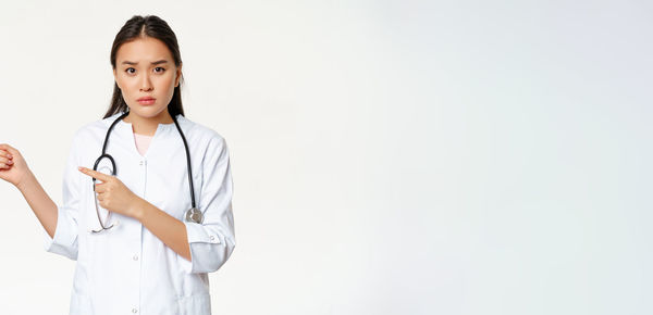 Portrait of doctor standing against white background