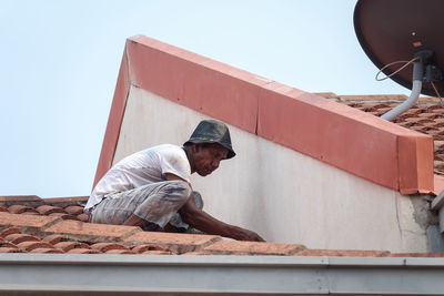 Man working on wall against clear sky