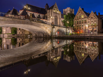 Bridge over river by houses at dusk