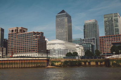 Canary wharf by river against sky