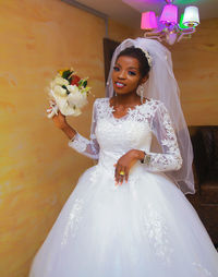 Portrait of bride standing against yellow background