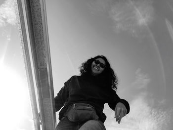 Portrait of young woman sitting against sky