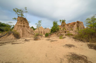 Rock formations in desert against cloudy sky