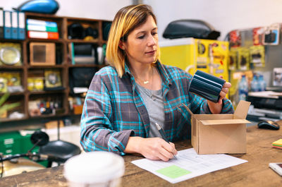 Portrait of blonde woman entrepreneur checking product received by courier to sell in local store