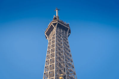 Low angle view of crane by building against clear blue sky