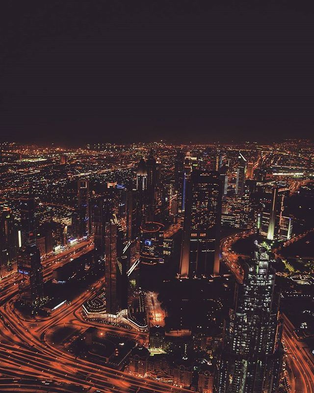 illuminated, night, city, cityscape, architecture, building exterior, built structure, high angle view, crowded, skyscraper, city life, modern, aerial view, dark, no people, capital cities, sky, office building, light, light trail