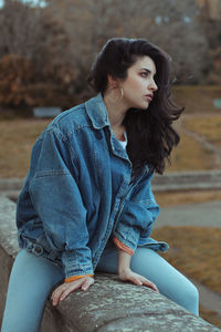 Young woman looking away while sitting outdoors