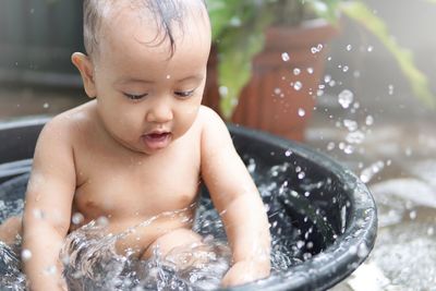 Close-up of baby playing with water in bathtub at bathroom