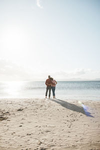 Mature couple standing at beach on sunny day