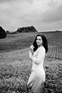 Portrait of smiling young woman standing on tea plantation