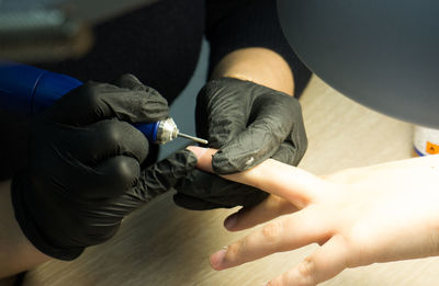 Close-up of beautician giving manicure to woman