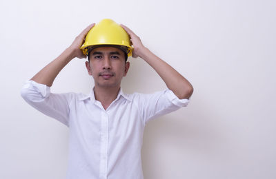 Portrait of young man standing against white background