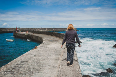 Woman standing on pier at sea