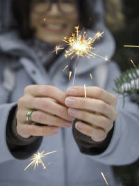 Smiling woman celebrates christmas or new year with sparkler. bengal fire, traditional firework