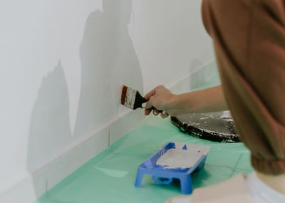 A young girl paints a wall with a brush.