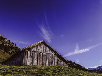 Panoramic view of barn on field against blue sky