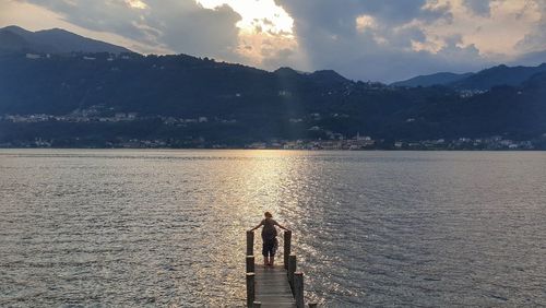 Rear view of couple standing on pier over lake during sunset