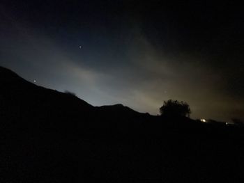 Low angle view of silhouette mountain against sky at night