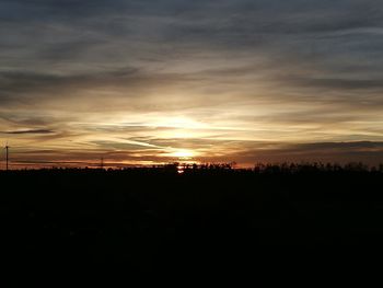 Silhouette landscape against dramatic sky during sunset