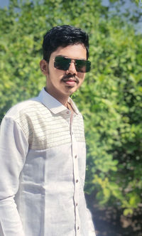 Portrait of young man wearing sunglasses standing outdoors