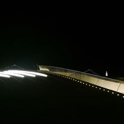 Illuminated suspension bridge against sky at night