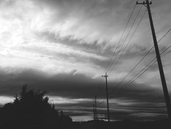 Low angle view of power lines against cloudy sky