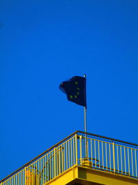 Low angle view of flag against clear blue sky