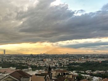 Cityscape against cloudy sky at sunset
