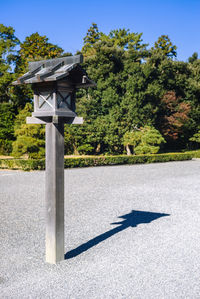 Information sign on road by trees against clear sky